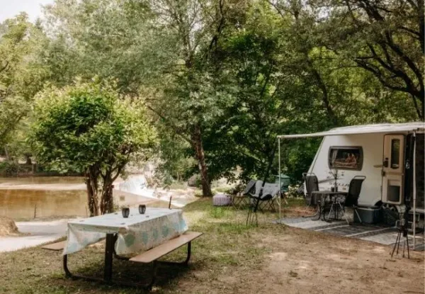 Emplacement avec une caravane devant une rivière