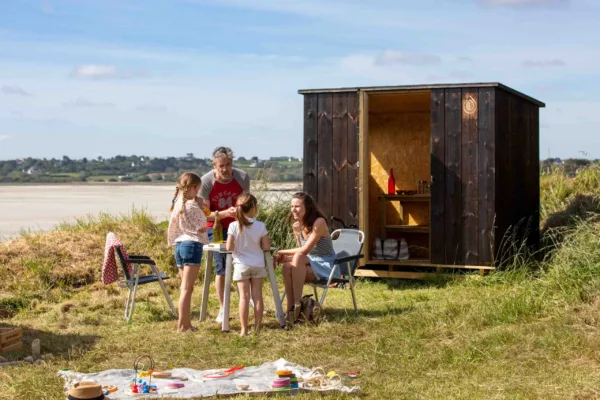 Une famille s'amusant devant une Slow Box (box avec sanitaires et cuisine privés) à coté de la mer
